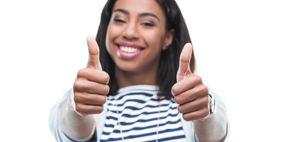 young woman smiling and giving two thumbs up