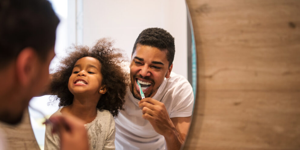 dad and daughter brushing teeth in bathroom