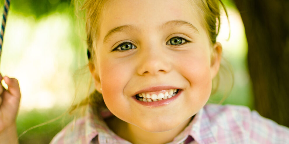 close up of little girl smiling at camera outside