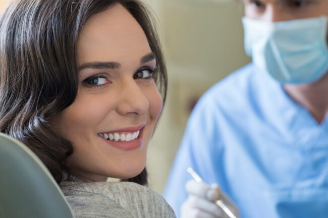 Smiling young woman receiving dental checkup with dentist