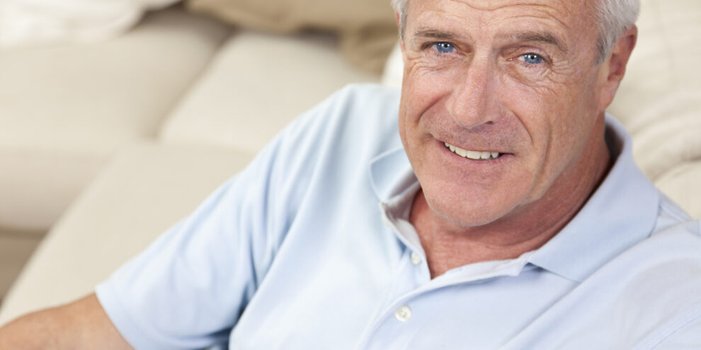 Happy and healthy senior man sitting on a sofa at home smiling and happy