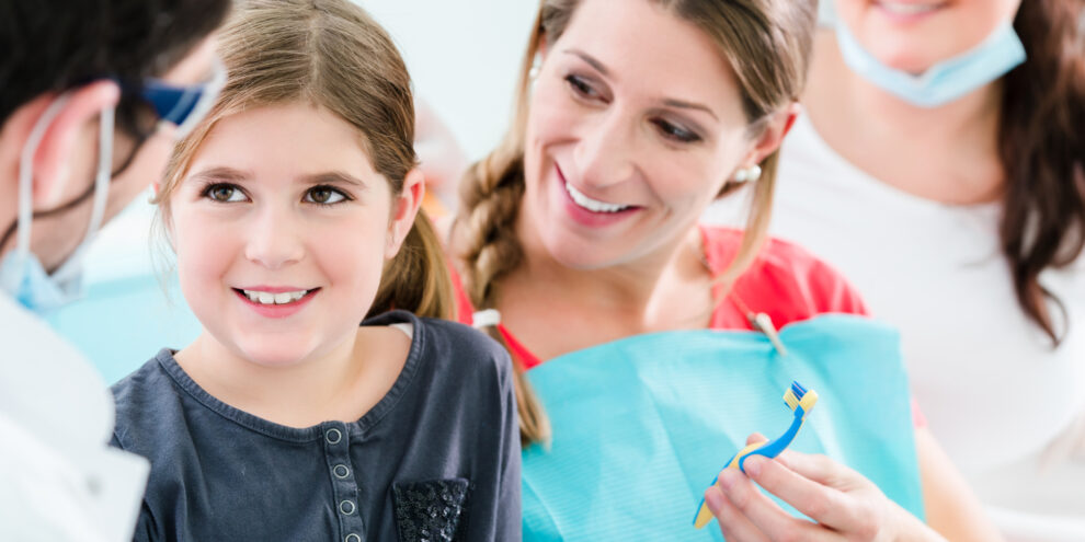 Family dentist and his assistant working with young girl and her pregnant mother