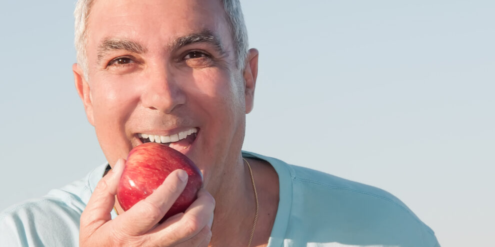 happy older man eating a red apple