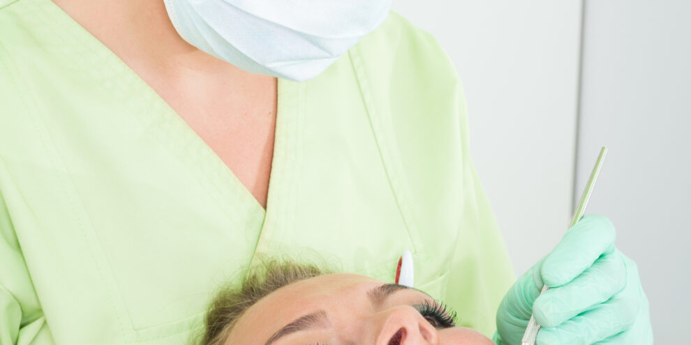 Female dentist performing dental cleaning on female patient