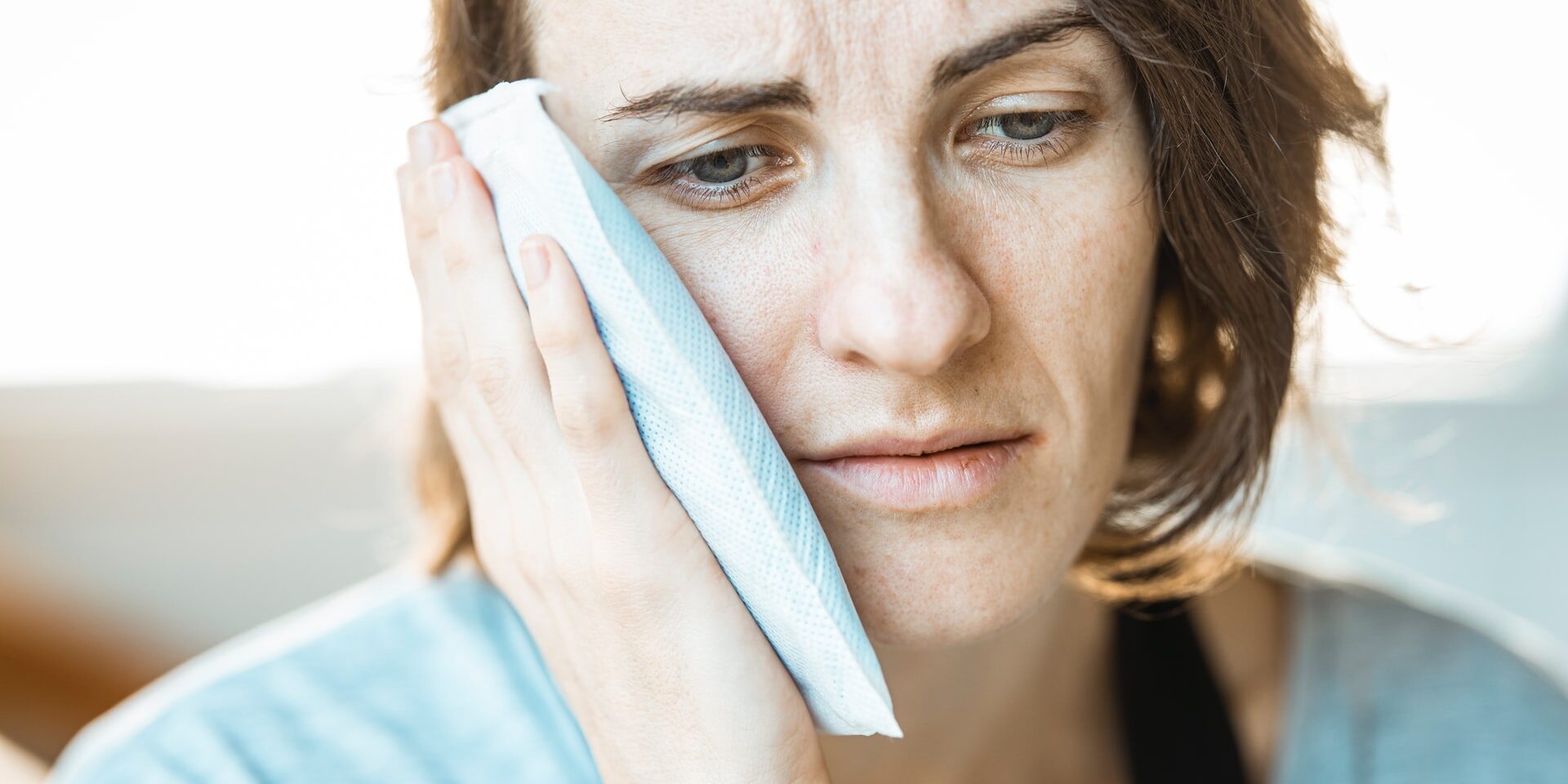 woman in pain holding ice pack to the side of her face