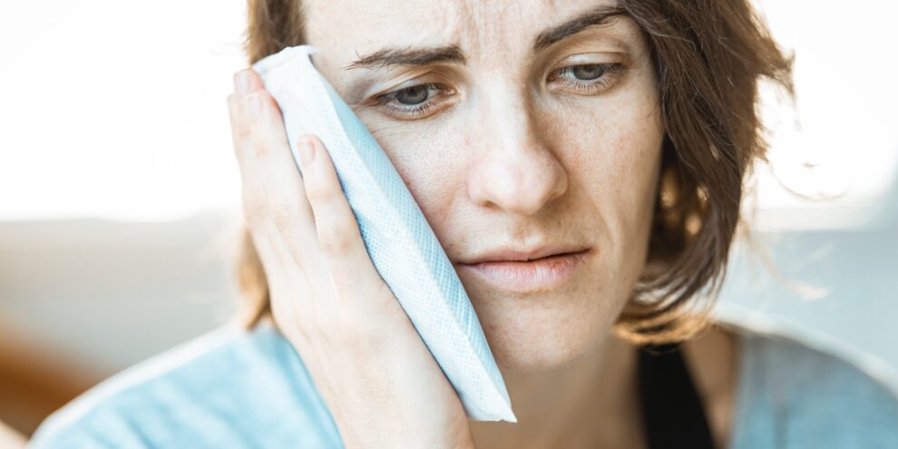woman in pain holding ice pack to the side of her face