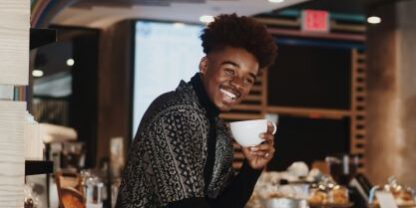 man showing off coffee cup and bright white smile
