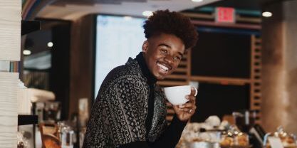 man showing off coffee cup and bright white smile