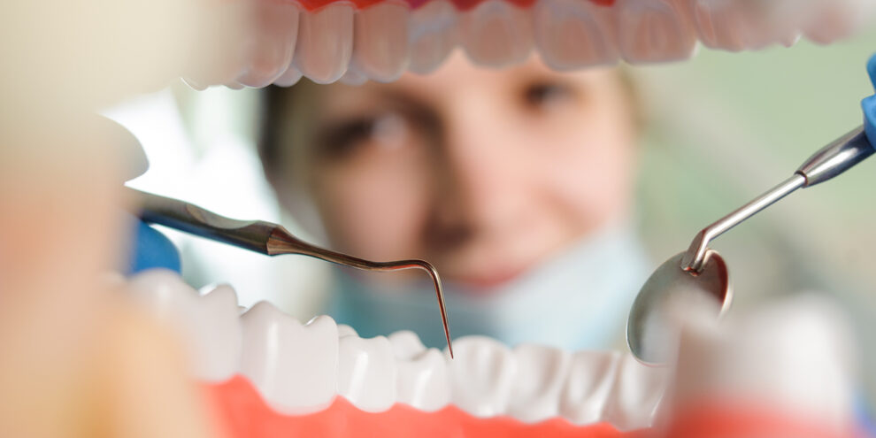dental hygienist using tools to inspect patient's mouth