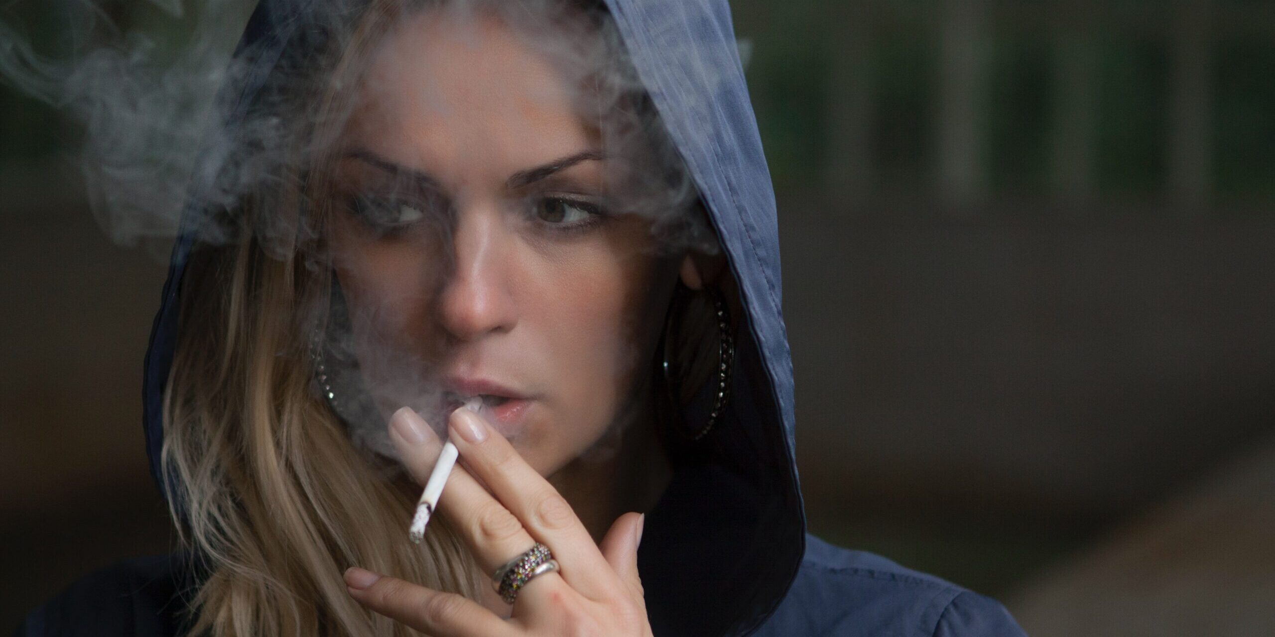 A woman smokes a cigarette, which indicates the origin of her bad breath