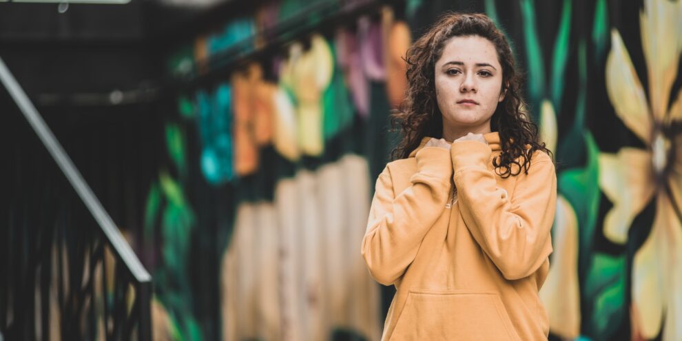 Young woman in yellow sweatshirt with clenched fists