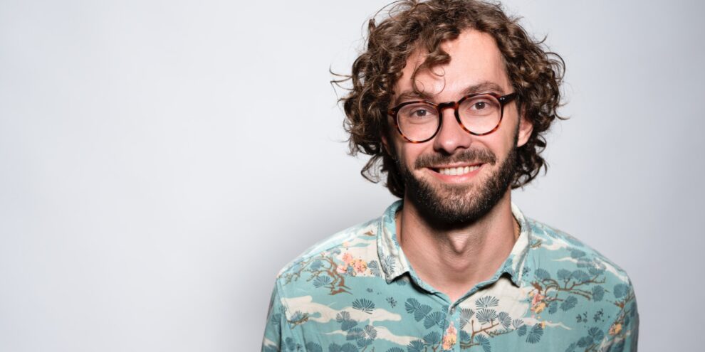 Man with curly hair and horn rimmed glasses
