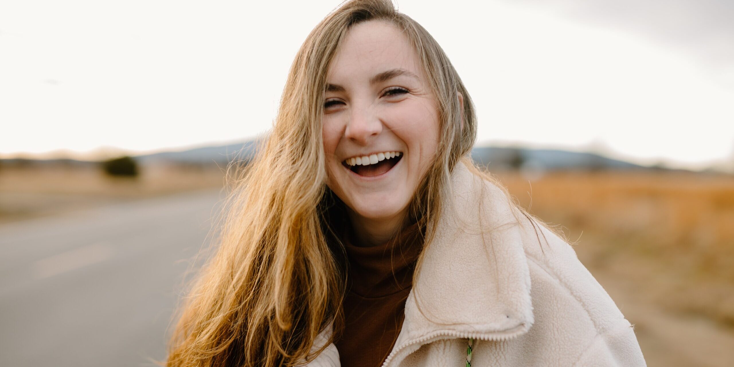 woman laughing and smiling at the camera on the side of the road