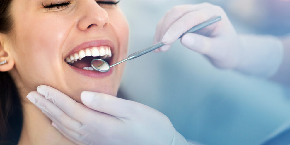 dentist placing mirror in woman's mouth during a dental checkup