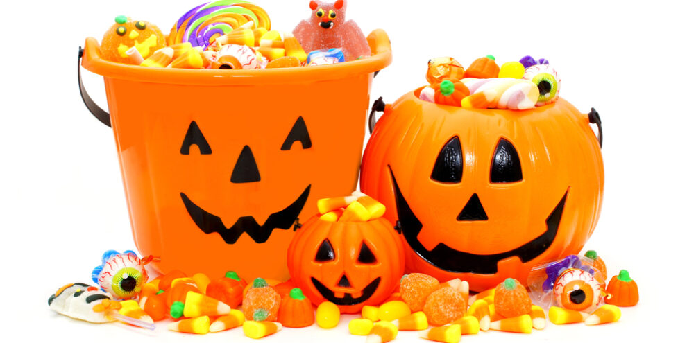 different Halloween candy buckets with halloween candy filled and spilling over