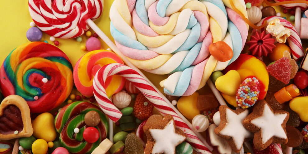 Various kinds of candy on yellow background