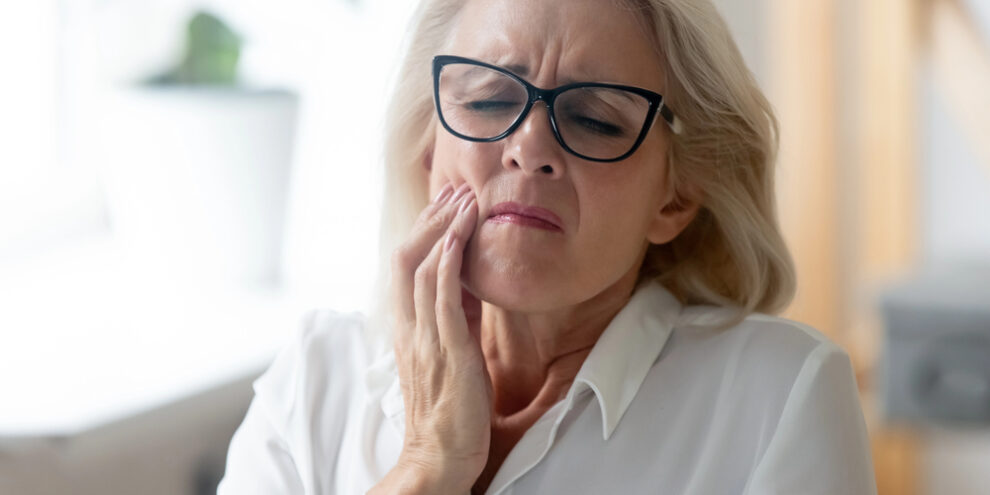 older woman feeling pain in her tooth because of dental filling