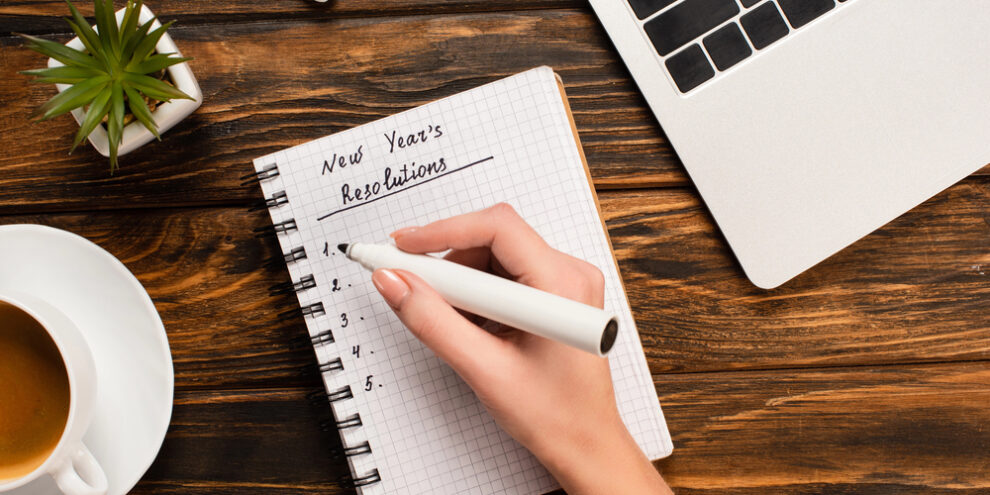 close up of woman's hand writing new year resolutions