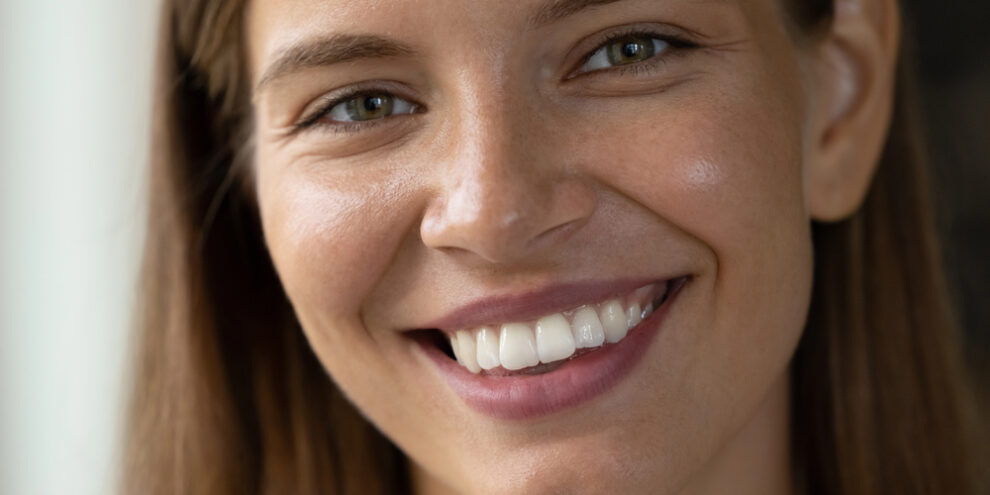 close up portrait of woman with brown hair, white round teeth, and big smile