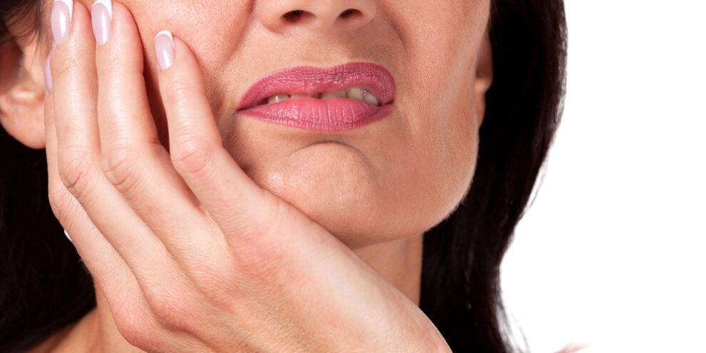 close up of woman touching her face in pain because of toothache