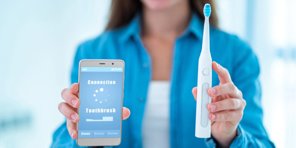 woman holding an electric toothbrush with a phone app